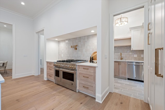 kitchen featuring light countertops, appliances with stainless steel finishes, light wood-style floors, ornamental molding, and a sink