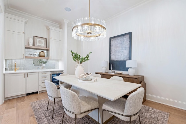 dining room featuring light wood-type flooring, wine cooler, crown molding, and an inviting chandelier