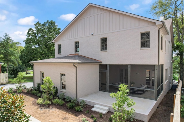 back of property with brick siding, a shingled roof, a patio, and french doors