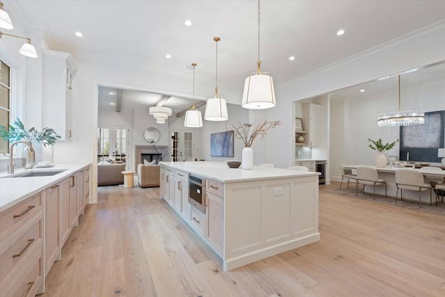 kitchen with light wood-type flooring, crown molding, open floor plan, and a sink