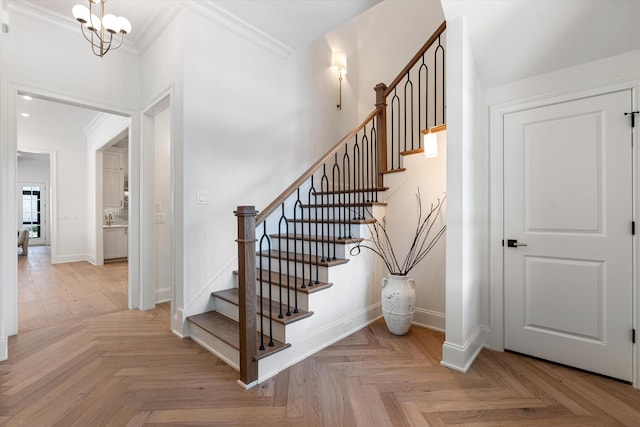 stairs with an inviting chandelier, baseboards, and ornamental molding