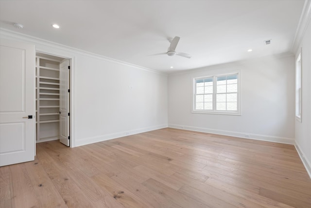 spare room with ornamental molding, light wood-type flooring, visible vents, and baseboards