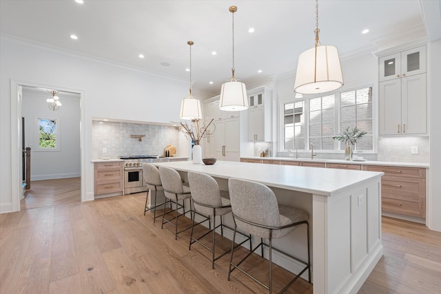 kitchen with light countertops, ornamental molding, high end stainless steel range oven, and light wood-style floors