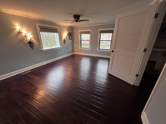 unfurnished room featuring baseboards, dark wood-type flooring, visible vents, and crown molding