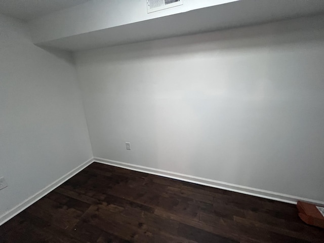 unfurnished room featuring baseboards, visible vents, and dark wood-type flooring