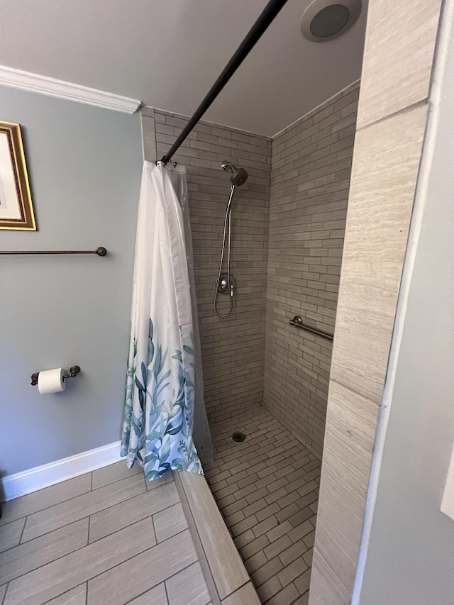 bathroom featuring ornamental molding, tiled shower, wood finish floors, and baseboards