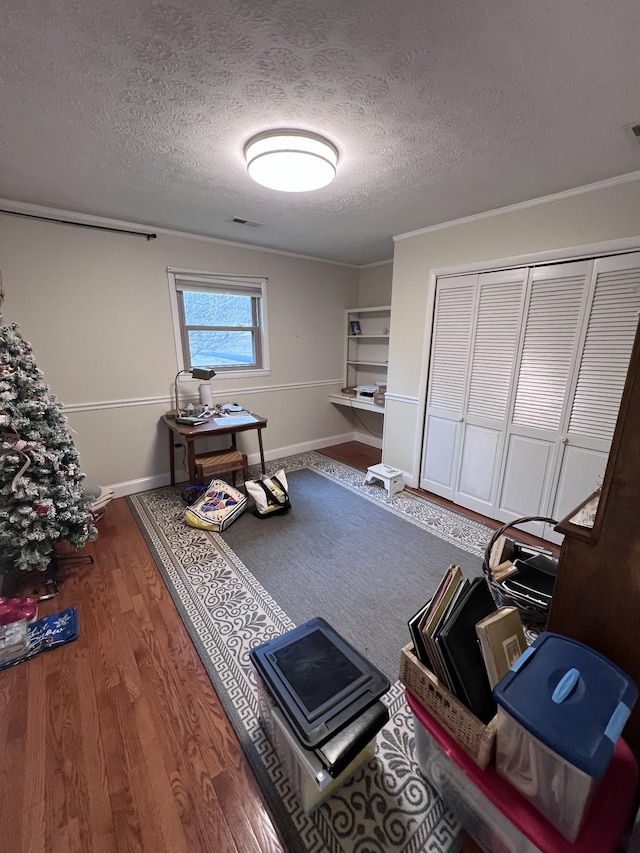 misc room with visible vents, a textured ceiling, baseboards, and wood finished floors