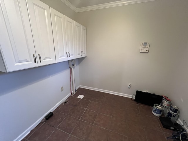 washroom with dark tile patterned floors, baseboards, ornamental molding, and cabinet space