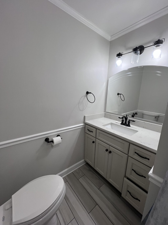 bathroom with toilet, ornamental molding, vanity, and baseboards