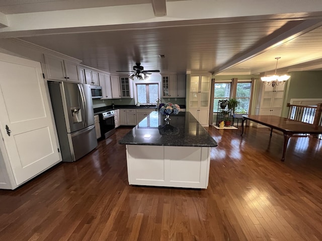 kitchen featuring dark wood finished floors, dark stone counters, a kitchen island, glass insert cabinets, and appliances with stainless steel finishes