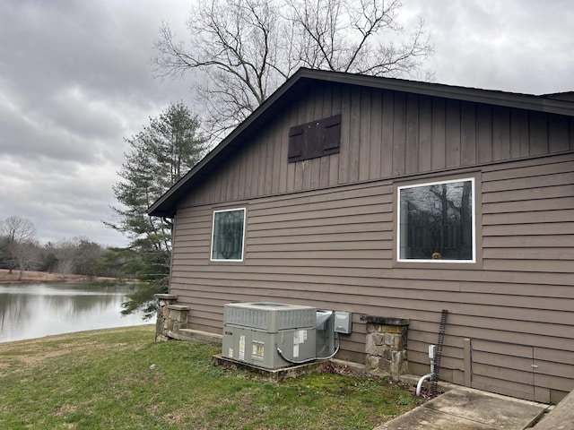 view of side of home featuring central air condition unit, a water view, and a yard