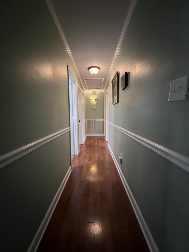 hallway featuring ornamental molding, dark wood-style flooring, attic access, and baseboards