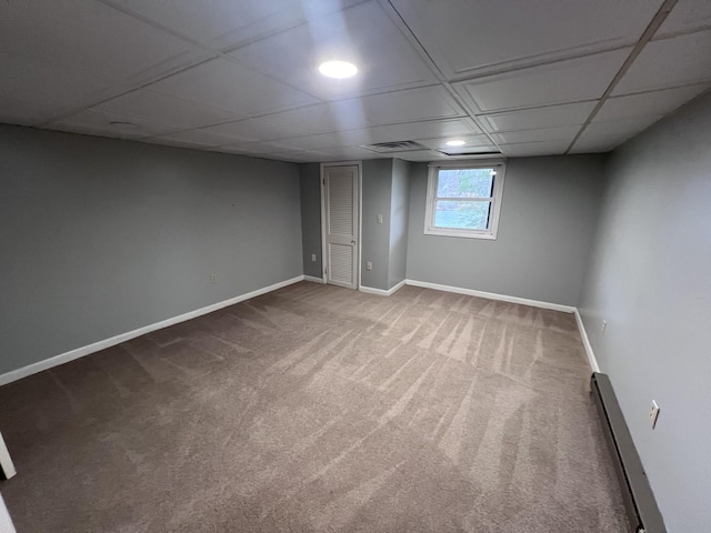 basement featuring visible vents, baseboards, a drop ceiling, a baseboard radiator, and carpet floors