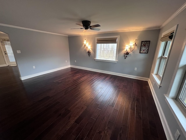 spare room featuring baseboards, arched walkways, dark wood finished floors, ceiling fan, and ornamental molding