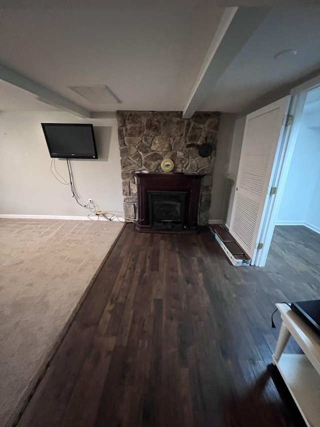 unfurnished living room with a fireplace, baseboards, wood finished floors, and beamed ceiling