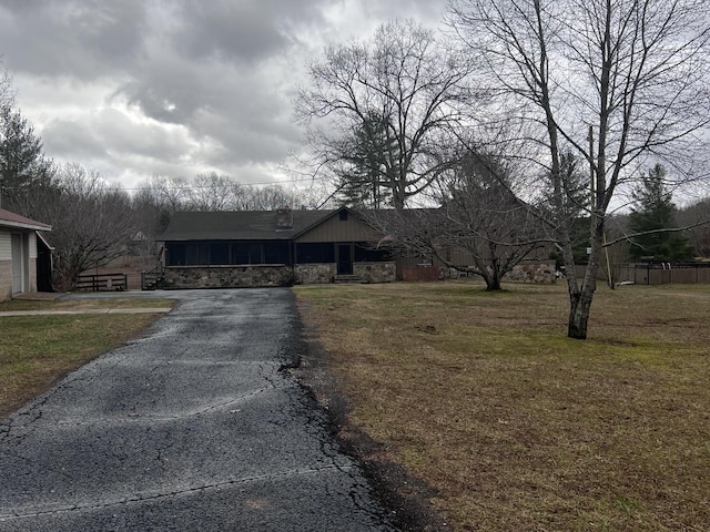 view of front of house with aphalt driveway, stone siding, and a front lawn