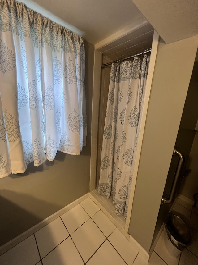 full bathroom with a stall shower, tile patterned flooring, and baseboards