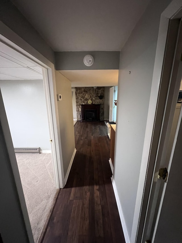 hall with dark wood-style flooring, a baseboard radiator, and baseboards