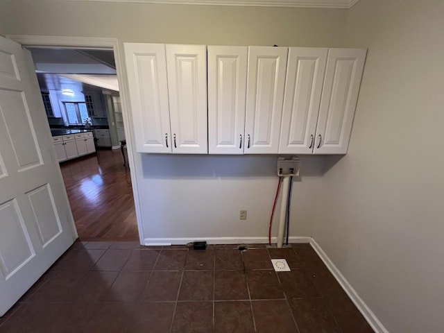 clothes washing area featuring dark tile patterned floors, washer hookup, cabinet space, and baseboards