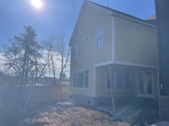 view of property exterior featuring crawl space, fence, and french doors