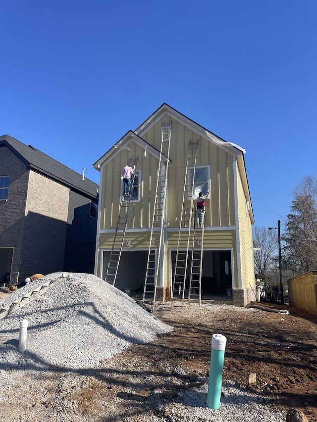 rear view of house with board and batten siding and driveway