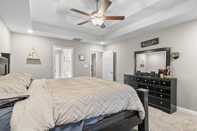 carpeted bedroom with a tray ceiling, visible vents, ceiling fan, and baseboards