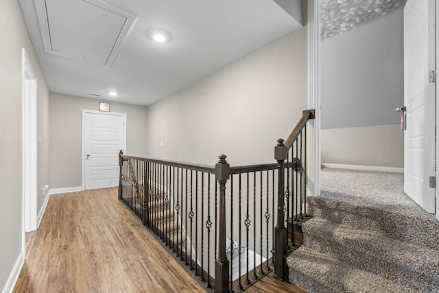 corridor with attic access, an upstairs landing, baseboards, and wood finished floors