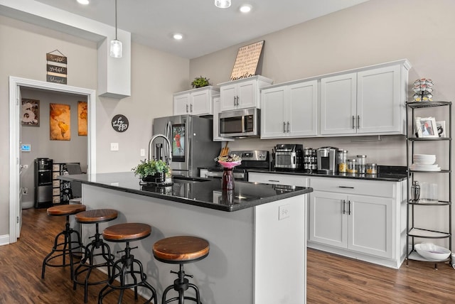 kitchen featuring appliances with stainless steel finishes, dark wood-style flooring, white cabinetry, and a breakfast bar area