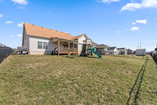 rear view of property featuring a fenced backyard, a playground, and a yard