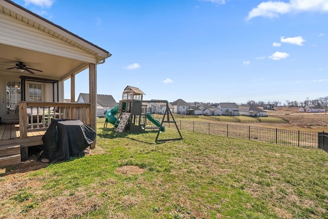 view of yard featuring ceiling fan, fence, a playground, and a wooden deck