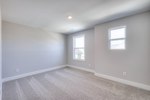 spare room with light carpet, visible vents, and baseboards