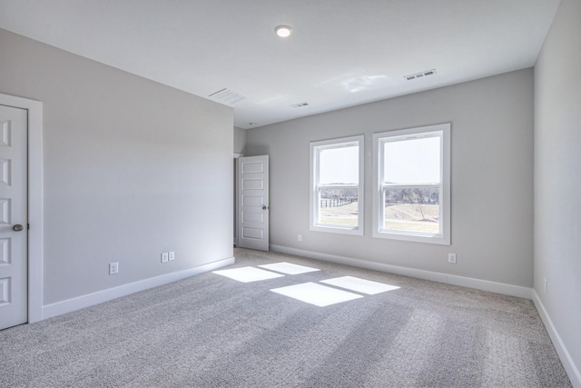 empty room featuring carpet, visible vents, and baseboards