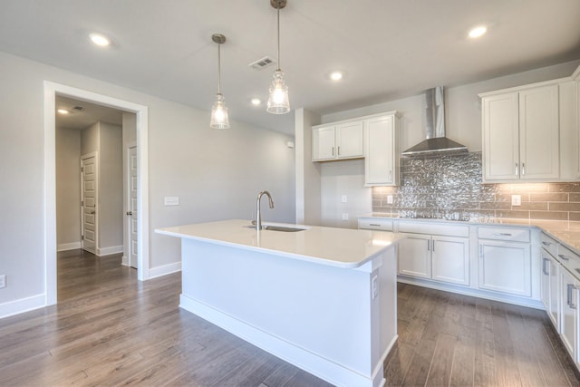 kitchen with dark wood-style floors, tasteful backsplash, visible vents, a sink, and wall chimney range hood