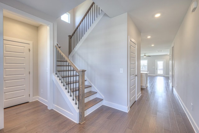 staircase with recessed lighting, wood finished floors, and baseboards