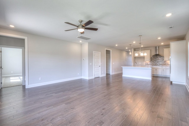 unfurnished living room featuring visible vents, ceiling fan, dark wood-type flooring, a sink, and recessed lighting