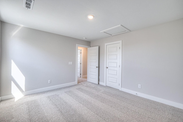 unfurnished bedroom with attic access, visible vents, baseboards, light colored carpet, and a closet