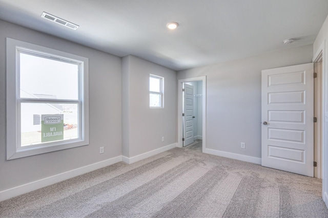 empty room featuring carpet, visible vents, and baseboards