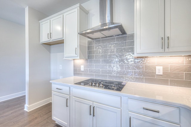 kitchen with baseboards, wall chimney exhaust hood, wood finished floors, black electric stovetop, and white cabinetry