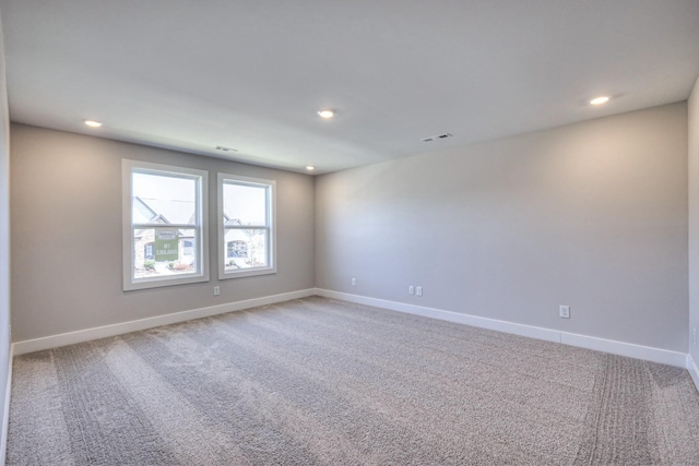 empty room with light colored carpet, visible vents, and baseboards