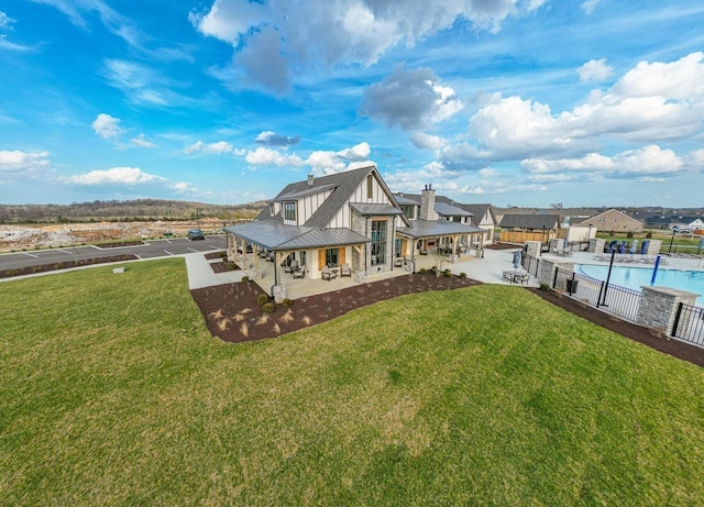 rear view of house featuring fence, a lawn, a fenced in pool, a standing seam roof, and a patio area