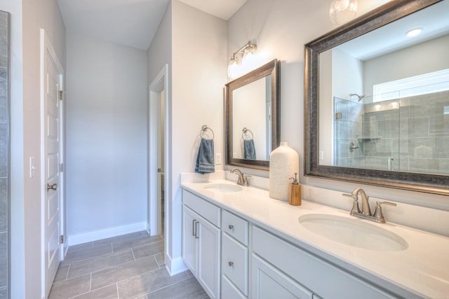 bathroom featuring tiled shower, a sink, baseboards, and double vanity