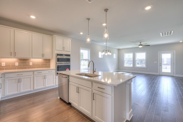 kitchen featuring dark wood-style flooring, a sink, visible vents, appliances with stainless steel finishes, and tasteful backsplash