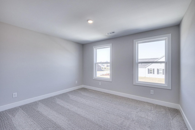 empty room featuring light carpet, baseboards, and visible vents