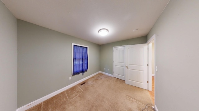 unfurnished bedroom with visible vents, light carpet, and baseboards