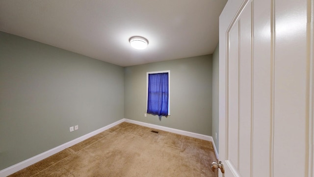 spare room with visible vents, light colored carpet, and baseboards