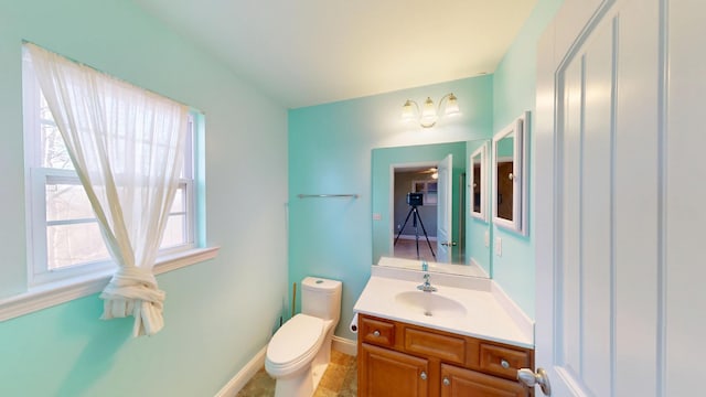 bathroom with toilet, baseboards, and vanity