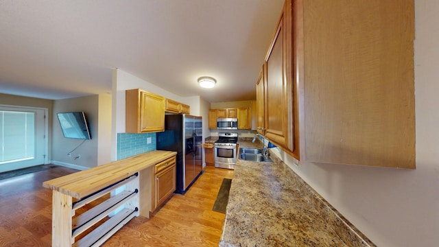 kitchen featuring light countertops, appliances with stainless steel finishes, light wood-type flooring, and a sink