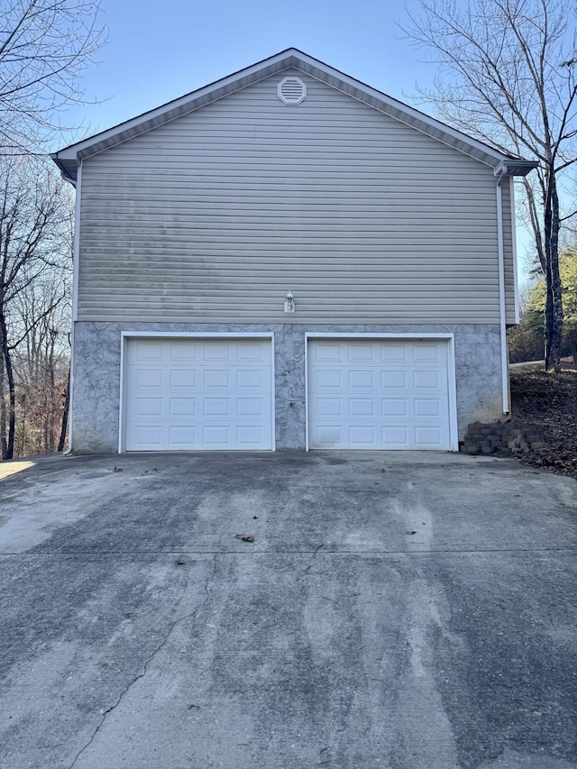 view of side of home featuring a garage and concrete driveway