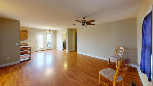 living area with baseboards, visible vents, ceiling fan, and wood finished floors