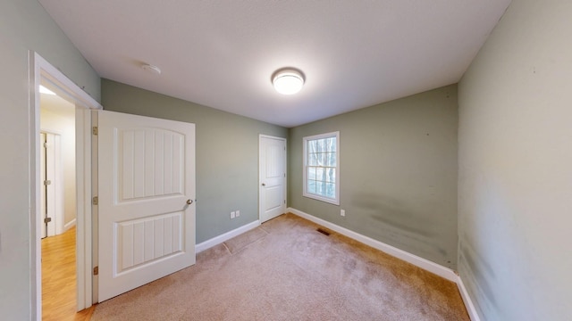 unfurnished bedroom with baseboards, visible vents, and light colored carpet